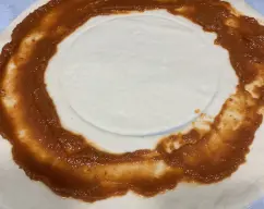 Step <p>Ponemos el tomate dejando un dedo de espacio por fuera y levantamos un poco la masa por los lados.</p> illustration