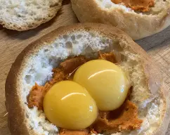 Step <p>Cortamos la parte de arriba del panecillo, como si fuera un sombrero, y vaciamos un poco la miga.</p><p>Separamos la clara de las yemas, ponemos en el fondo del panecillo la sobrasada y encima la yema salpimentamos y reservamos. </p> illustration