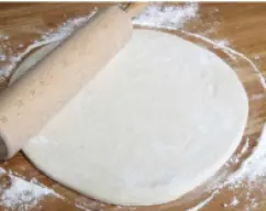 Step <p>Estiramos con la ayuda del rodillo y formamos un círculo. Marcándonos un punto central y con la ayuda del cuchillo dividimos el centro en 6 partes.</p> illustration