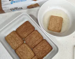 Step <p><span style="font-weight: normal;">Pon el álmibar y el licor en un bol y mezcla. Remoja las galletas por las dos caras unos segundos y disponlas dentro de una bandeja o un molde cubriendo el fondo. Cubre con una capa de crema y repite la misma operación otra vez (2 capas de galleta alternadas con la crema). Guarda en la nevera de 3 a 4 horas y decora con trozos de melocotón y unas hojitas de menta.</span></p> illustration